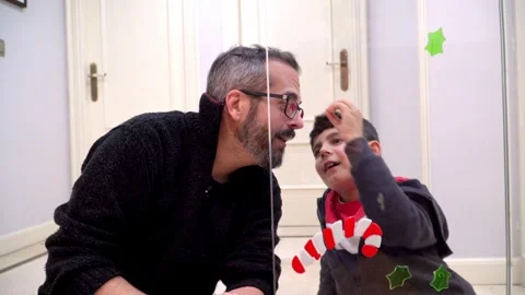 Boy having fun putting Christmas decoration on father’s glasses Stock Footage 345253089