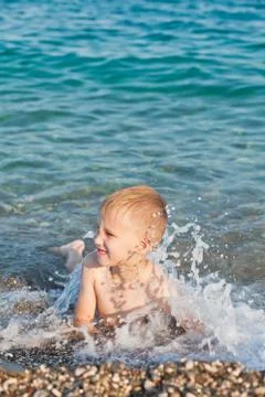 Boy having fun in sea or ocean waves in a summer sunny day. Ocean coast and b Stock Photos