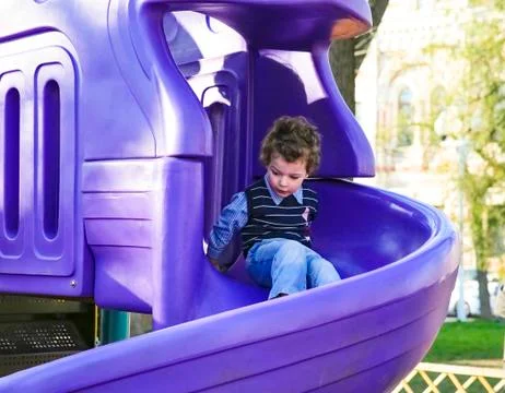 Boy having fun sliding down on the playground. kid playing outdoors. copy space Stock Photos