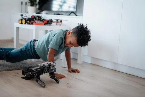 Boy having fun with small robot at home as part of STEM learning. 스톡 사진