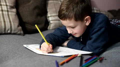 Boy having fun on sofa, boy was coloring cartoons on coloring book at home Stock Footage 170262914