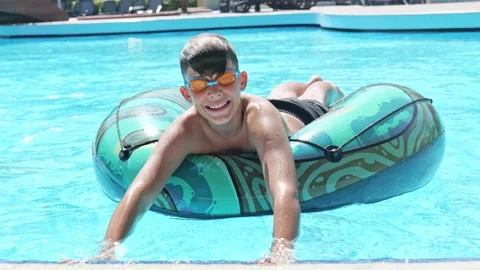 Boy Having Fun in the Swimming Pool On Inner Tube. Summer Vacation Fun. Stock Footage 169957836