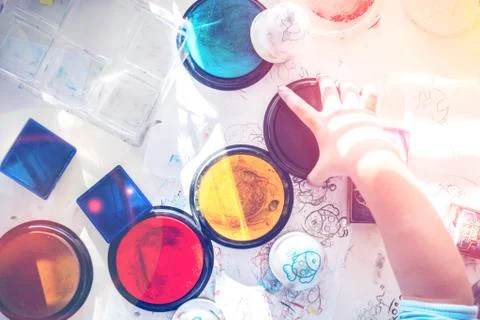 Boy is having fun while playing with stamps and tempera paints on wooden work Stock Photos
