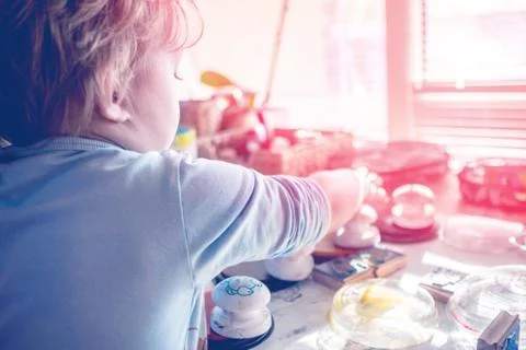 Boy is having fun while playing with stamps and tempera paints on wooden work Stock Photos