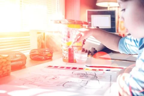 Boy is having fun while playing with stamps and tempera paints on wooden work Stock Photos