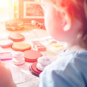 Boy is having fun while playing with stamps and tempera paints on wooden work Stock Photos