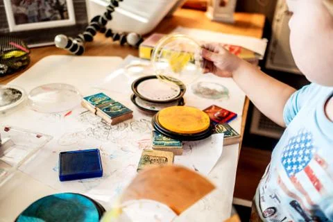 Boy is having fun while playing with stamps and tempera paints on wooden work Stock Photos