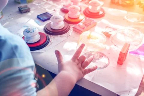 Boy is having fun while playing with stamps and tempera paints on wooden work Stock Photos