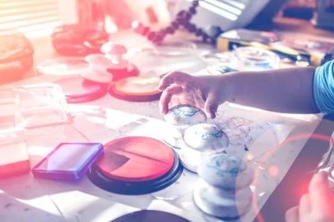Boy is having fun while playing with stamps and tempera paints on wooden work Stock Photos