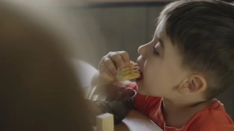 Boy having healthy breakfast sitting at kitchen table, eating waffles with jam Stock Footage 196206609