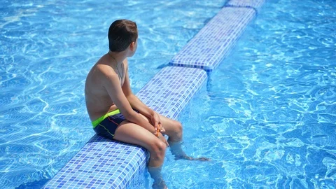 Boy having a rest in the pool. Active boy sitting on the swimming pool Vidéo 119146379