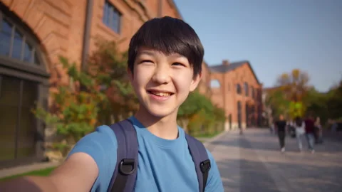 Boy having a video call talking at camera outdoors. Realtime Stock Footage 233931827