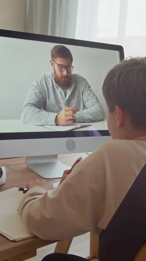 Boy Having Virtual Class with Male Tutor on Computer at Home Stock Footage 332780615