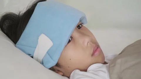 Boy with header cold pad sleeping on bed Stock Footage 137158911