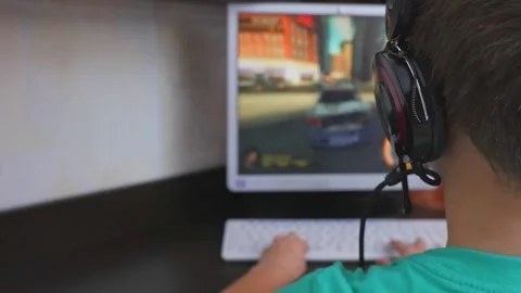 A boy with headphones is playing a computer game in front of a personal compu Stock Footage 168486586