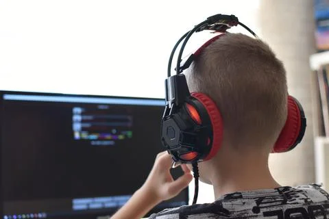 Boy with headphones sits at computer playing online games. children's gamblin Stock Photos