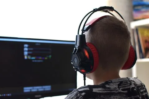 Boy with headphones sits at computer playing online games. children's gamblin Stock Photos