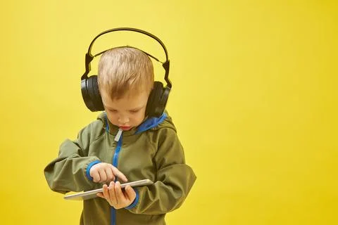 A boy with headphones is studying a tablet computer Foto stock