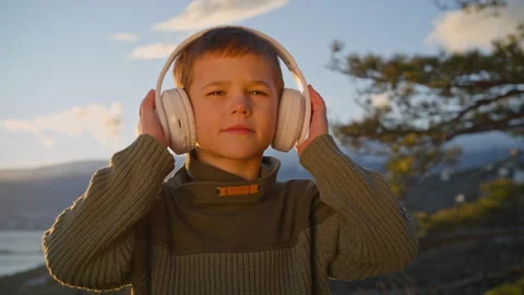 A boy with headphones. The sun is setting on a spring evening. Stock Footage 302312178