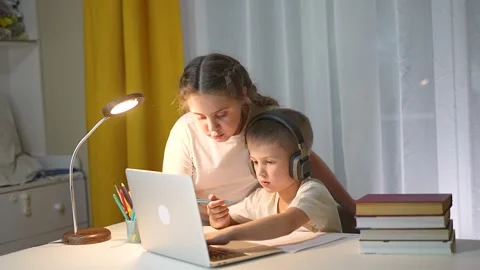 Boy in headphones writes on paper while girl helps studying. Girl explains Stock Footage 318446307