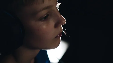 A boy with a headset on his head looks thoughtfully into the TV screen Stock Footage 111844019