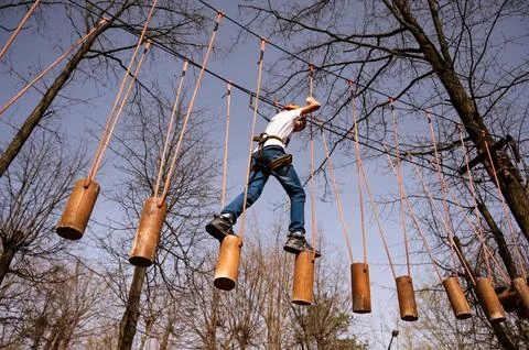 A boy in a helmet climbs a rope park in the spring Stock Photos