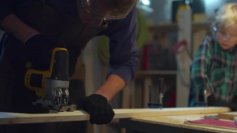 The boy helps dad to cut a board. Sliding Stock Footage 128180036