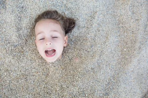 Boy hidden in the sand on the beach Stockfoto's