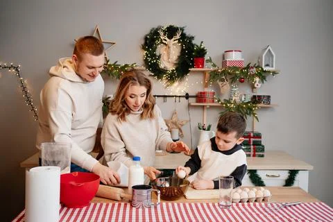 Boy himself tries to break egg. happy and beautiful family in new year's kitchen Stock Photos