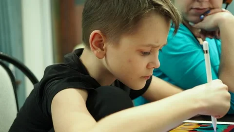 A boy with his mother draws on a tablet with a pencil Stock Footage 146161611