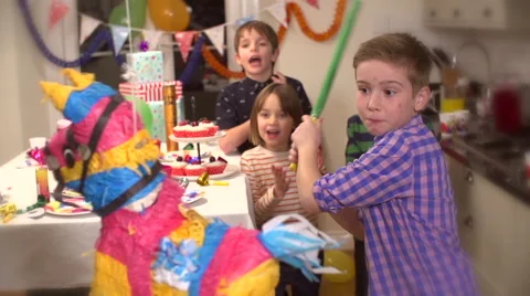Boy hitting a pinata at party while his friends cheer him up in slow motion Stock Footage 46160703