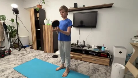 Boy hitting ping pong paddle with hand in living room, playful child activity, Stock Footage 336965620
