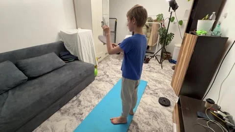 Boy hitting ping pong paddle with hand in living room, playful child activity, Stock Footage 336965624
