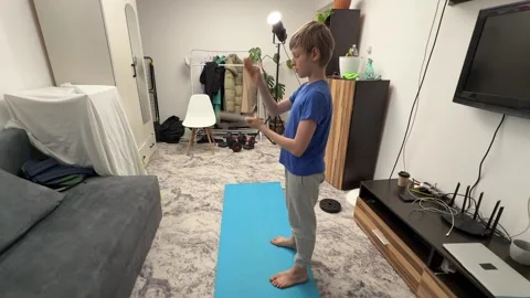 Boy hitting ping pong paddle with hand in living room, playful child activity, Stock Footage 336965628
