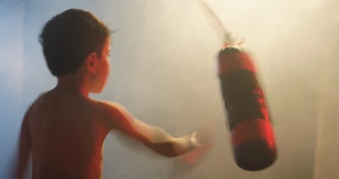 Boy hitting the punching bag on dark 스톡 동영상 112069646