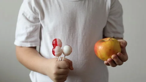 The boy is holding a candy and an apple. Stock Footage 147452523