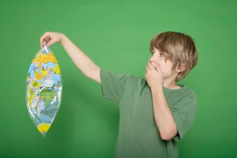 Boy holding deflated air globe against green background Stock Photos