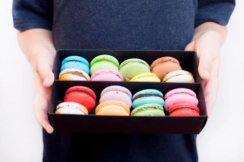 Boy holding dessert macarons in black wooden box Stock-Fotos