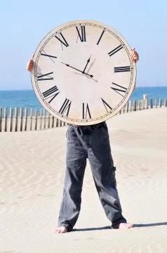 Boy Holding a Large Clock on the Beach Stock Photos