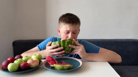 Boy holding large watermelon slice with two hands and eating it, summer fruit Stock Footage 337405944