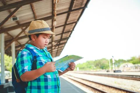 The boy is holding a map waiting for the train to travel. Photos