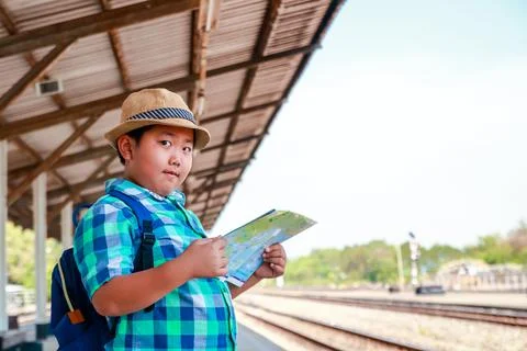 The boy is holding a map waiting for the train to travel. Stock Photos