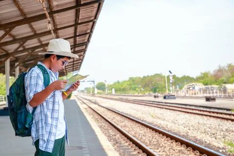 The boy is holding a map waiting for the train to travel. Photos