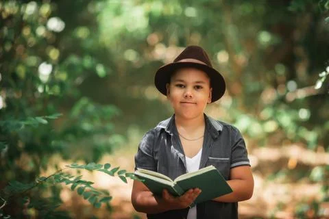 Boy holding an open book looking at camera in forest Stock Photos