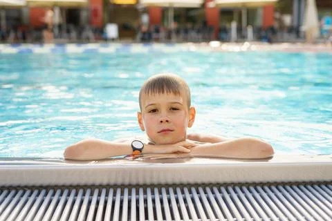 Boy holding onto the side of a pool, a boy swimming in an outdoor pool Stock Photos