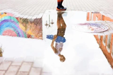 A boy holding a skiing board reflected in a pool of water. Stock Photos