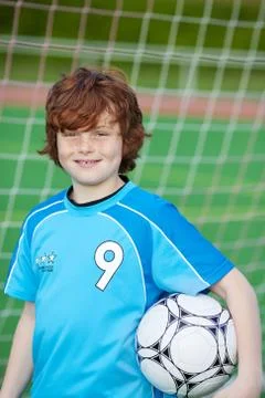 Boy holding soccer ball against net Stock Photos