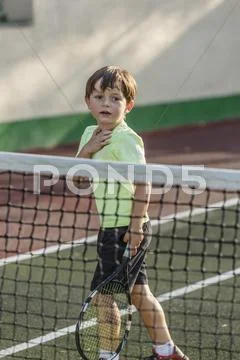 Boy Holding Tennis Racket While Standing On Field