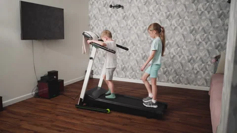 Boy Holding Treadmill Handle While Girl Carefully Walks Behind Stock Footage 310206402