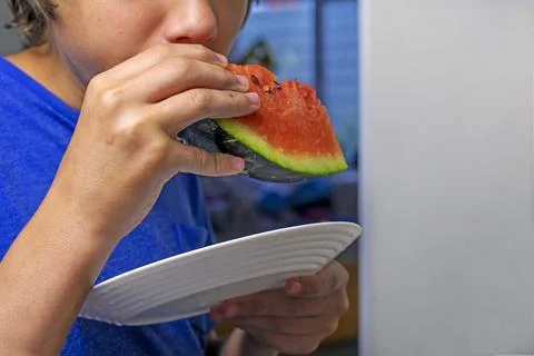 Boy holding a triangular slice of watermelon in his hands with his mouth open Stock Photos